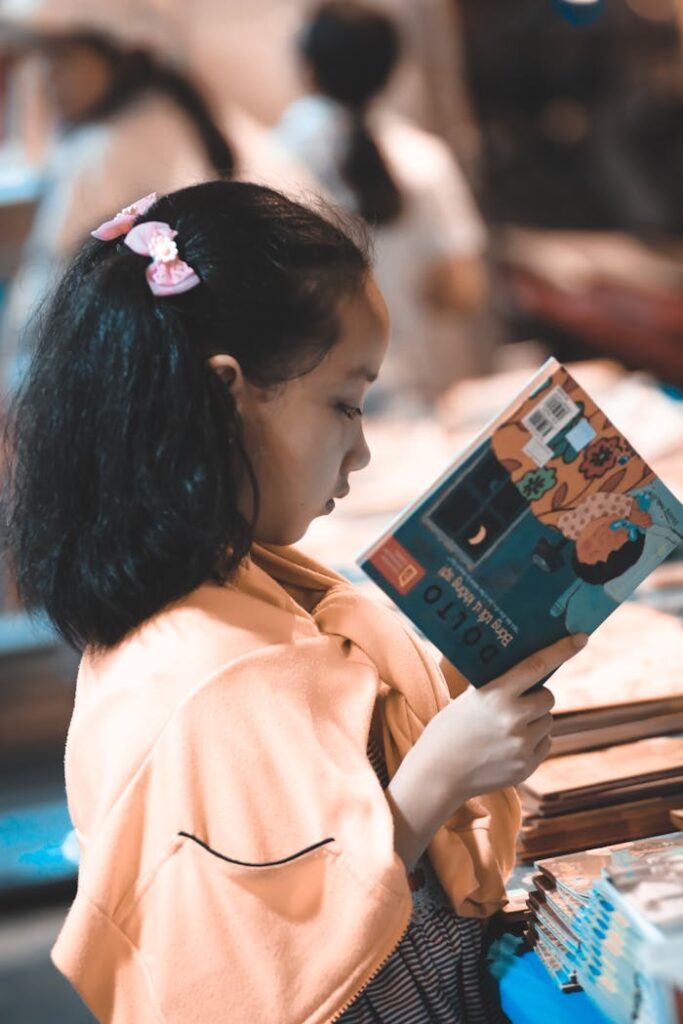 Online vs Offline Tuition – Which is Better for Students? Focused young girl reading a colorful book indoors, perfect for educational themes.
