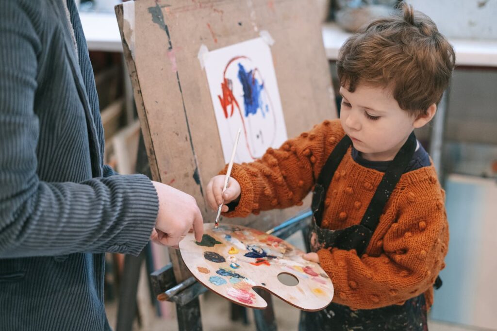 Building Confidence in Students Beyond Academics Young boy learning to paint with teacher's guidance during art class.
